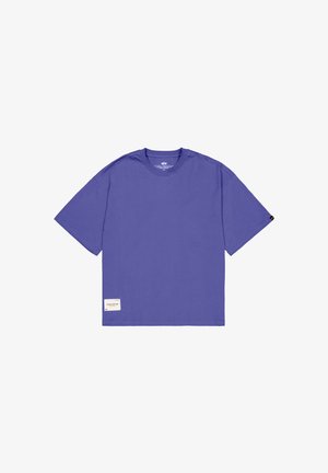 Paarse katoenen t-shirt met korte mouwen, ronde hals en een rechthoekig wit label op de linkeronderkant met tekst. Eenvoudig, oversized ontwerp.