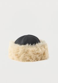 Black faux leather hat with a wide, fluffy beige faux fur band. Round shape, featuring visible stitching on the leather portion.