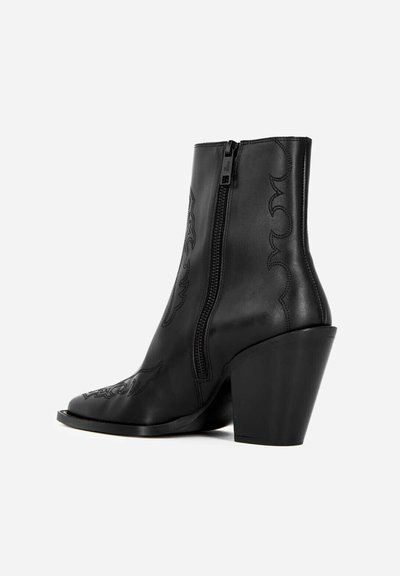 Black leather ankle boot with western-style stitching, pointed toe, side zipper, and chunky tapered heel against white background.