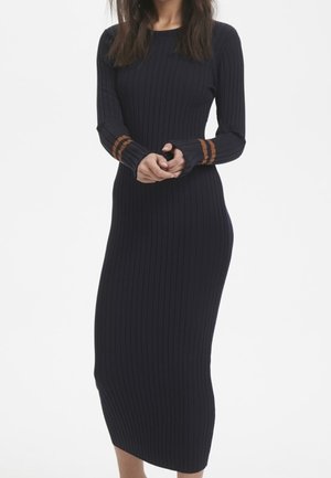 Prążkowana, długorękawowa sukienka dzianinowa w ciemnym granacie z kontrastującymi brązowymi paskami na mankietach. Dopasowana sylwetka, długość do kolan.