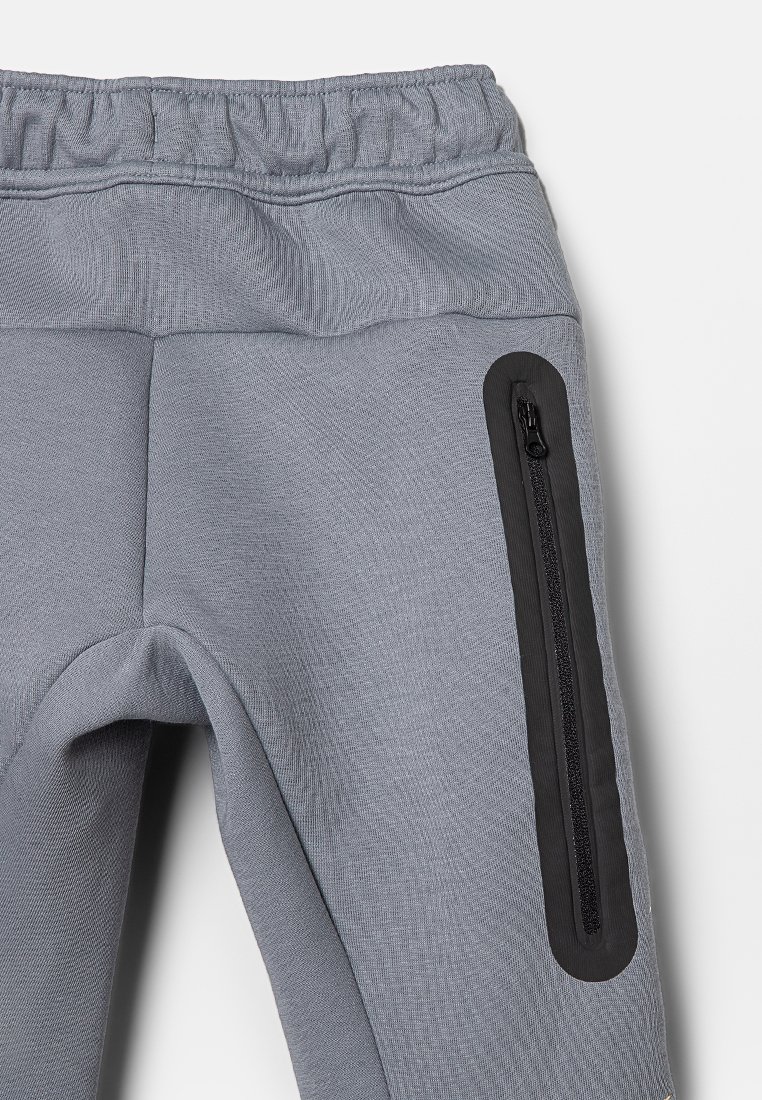 Pantaloni sportivi grigi con una finitura testurizzata, dotati di una tasca con zip nera sul lato e di una vita elasticizzata per il massimo comfort.