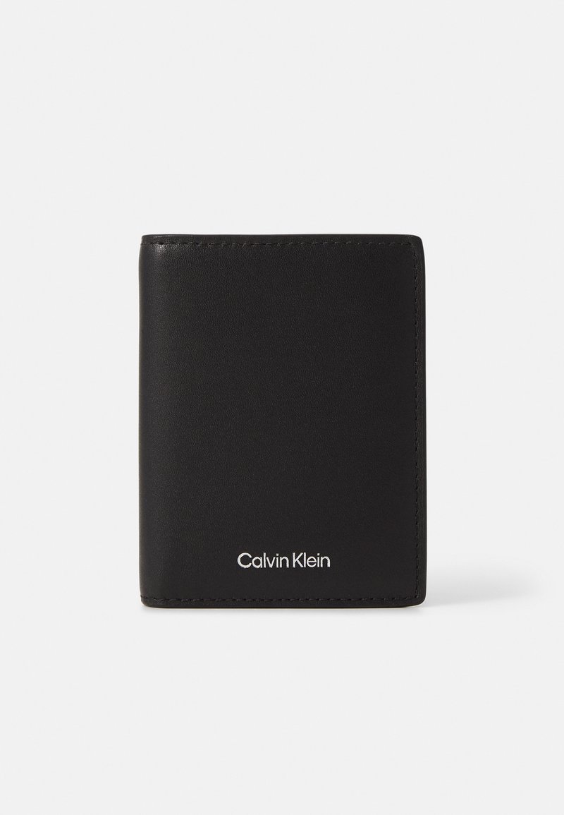 Svart lær lommebok med en jevn tekstur, minimalistisk design, sammenleggbar form og sølvfarget Calvin Klein-logo på forsiden.
