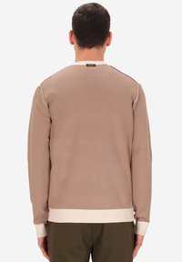 Maglione marrone a maglia con polsini e orlo color crema a coste. Cuciture decorative sulle spalle, progettato per una vestibilità aderente in un tessuto morbido.