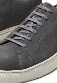 Graue Wildledersneaker mit grauen Schnürsenkeln und einer weißen Gummisohle. Mit Nähdetails und einer glatten, strukturierten Oberfläche.