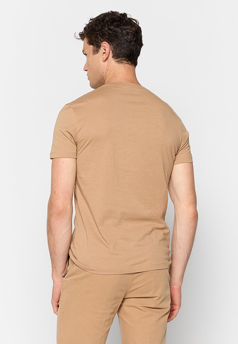 Beige Rundhals-T-Shirt aus weichem Baumwollmaterial, kurze Ärmel, figurbetontes Design und glatte Textur. Keine sichtbaren Muster oder Metallteile.