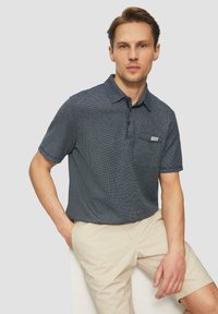 Navy kurzes Polohemd mit strukturiertem Muster, Brusttasche und Knopfleiste mit drei Knöpfen; kombiniert mit hellen Khaki-Shorts.