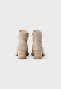 Beige semsket støvler med rund tå, sidelukking og ribbet trehæl. Glatt tekstur og minimalistisk design.