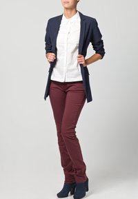 Blazer azul marino, camisa blanca con cuello, pantalones ajustados color burdeos y botines de tacón azules. Texturas suaves y diseño de corte entallado.