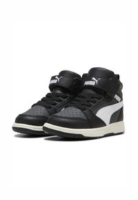 Zapatillas altas en negro y blanco hechas de cuero, con puntera perforada, diseño con cordones y una correa de Velcro alrededor del tobillo.