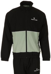 Zwarte trainingsjack met een mintgroen paneel, ritssluiting aan de voorkant, hoge kraag en witte accenten. Voorzien van elastische manchetten en een logo op de borst.