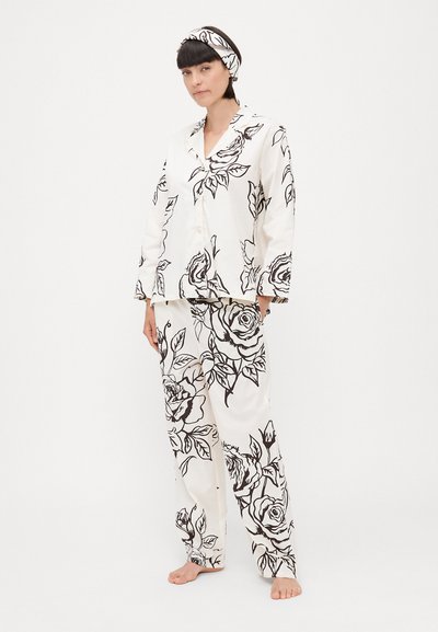 Pijamale albe cu un model floral negru; tops cu mânecă lungă, cu nasturi și pantaloni largi; include o bentiță asortată.