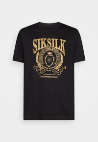 T-shirt en coton noir avec un design imprimé doré incluant du texte et un emblème. Manches courtes et col ras du cou avec une coupe normale.