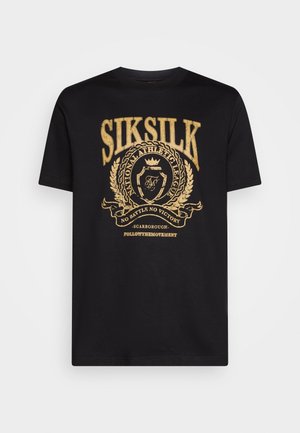 T-shirt en coton noir avec un design imprimé doré incluant du texte et un emblème. Manches courtes et col ras du cou avec une coupe normale.