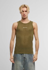 Canotta a maglia verde oliva con design a rete, caratterizzata da un colletto tondo e lettering bianco lungo il petto. Vestibilità non strutturata.