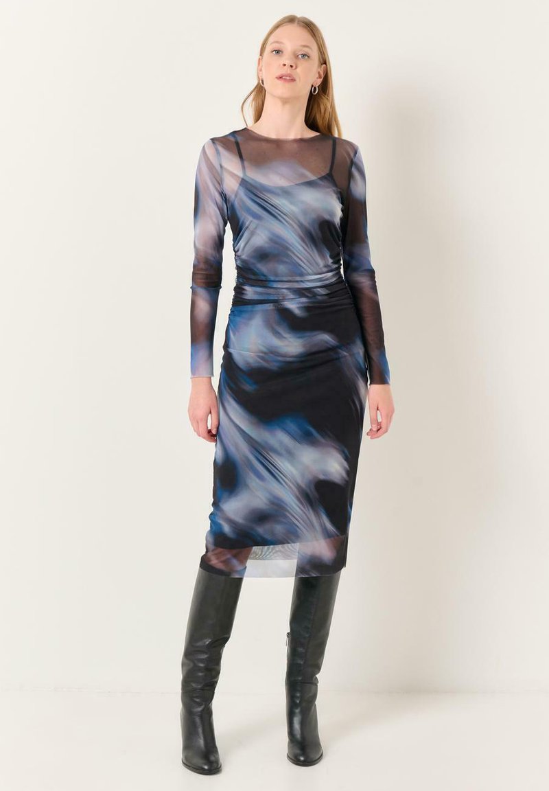 Robe à manches longues présentant un motif tourbillon bleu et noir, fabriquée en tissu transparent avec une silhouette ajustée, associée à des bottes noires jusqu'aux genoux.