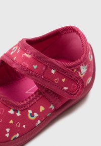 Pink fabric shoe with a rounded toe, featuring a Velcro strap. Design includes colorful unicorns, rainbows, and hearts on the surface.