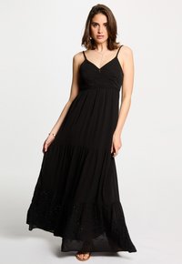 Robe maxi noire avec bretelles spaghetti, design en couches, accents brodés sur l'ourlet, fabriquée en tissu léger.