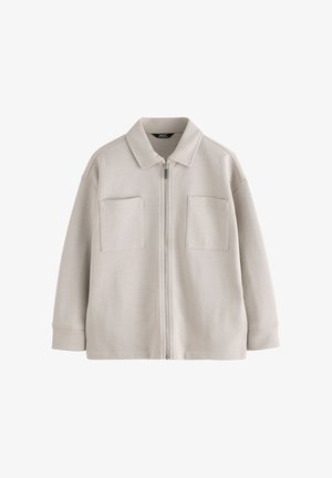 Lichtbeige jas met rits en kraag en twee vierkante zakken aan de voorkant, gemaakt van zachte stof met lange mouwen en een comfortabele pasvorm.