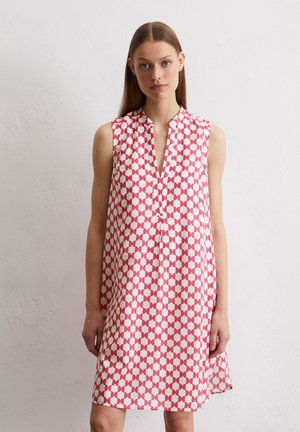 Sleeveless A-line dress in white with a red geometric pattern, featuring a V-neck and side slits for ease of movement. Smooth texture.