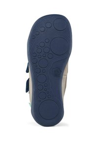 Shoe sole with a textured blue rubber bottom featuring circular and oval patterns. The edges are light beige and show design transition details.