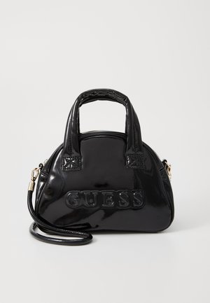 Sac à main en cuir verni noir avec un design arrondi, des poignées supérieures et une bandoulière amovible. Présente le logo "GUESS" en relief.