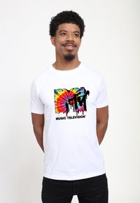 Hvid t-shirt med et farverigt tie-dye MTV logo-design med dryppende maleffekt, ledsaget af teksten "MUSIK TELEVISION" i sort.