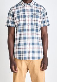 Koszula z krótkim rękawem, zapinana na guziki, w niebieską, białą i bordową kratkę. Posiada kieszeń na piersi oraz zaokrąglony dół, wykonana z lekkiego materiału.