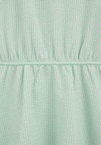 Tissu vert clair avec un motif de rayures verticales texturées et une couture froncée créant un effet de taille cintrée.