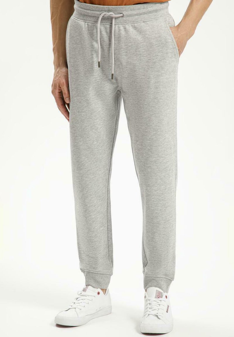 Szare dresowe spodnie z miękkiego materiału, z elastycznym pasem na sznurki, bocznymi kieszeniami i ściągaczami na kostkach. Subtelny detal logo na nodze.