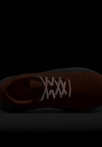 Scarpa sportiva rossa con una tomaia testurizzata, lacci riflettenti e suola nera. Il design presenta una costruzione senza cuciture per il massimo comfort.