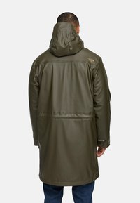 Olijfgroene waterdichte collectie met een capuchon, met een gladde, glanzende textuur, gestikte naden en een logoaccent op de schouder.