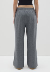Graue Sweatpants mit weitem Beindesign, aus weichem Stoff gefertigt. Sie verfügen über einen elastischen Bund und dezente Nähte am Saum.