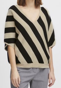Beżowy i czarny sweter w paski z dekoltem w kształcie V, krótkimi rękawami i luźnym krojem. Miękka tekstura i kontrastowe paski tworzą charakterystyczny wzór.