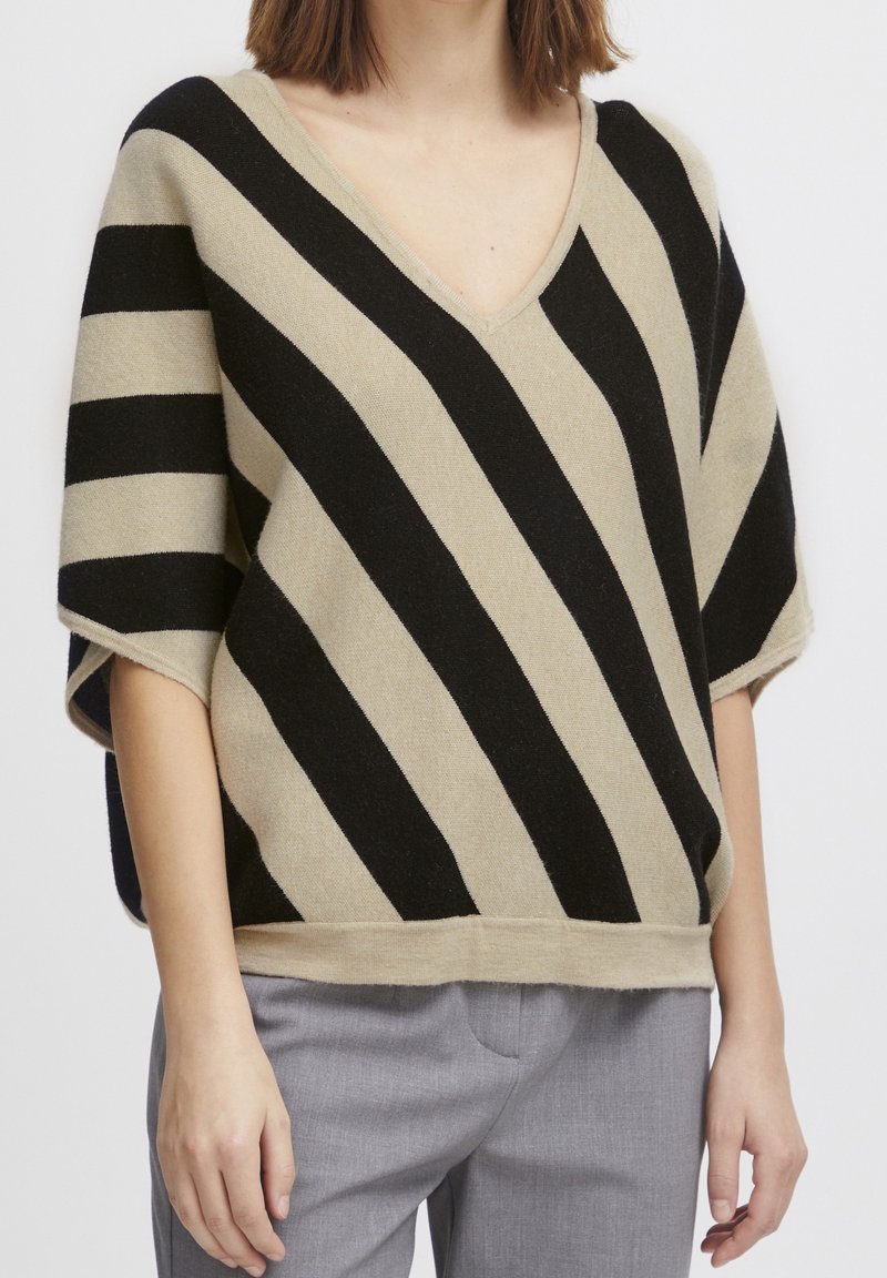 Beżowy i czarny sweter w paski z dekoltem w kształcie V, krótkimi rękawami i luźnym krojem. Miękka tekstura i kontrastowe paski tworzą charakterystyczny wzór.