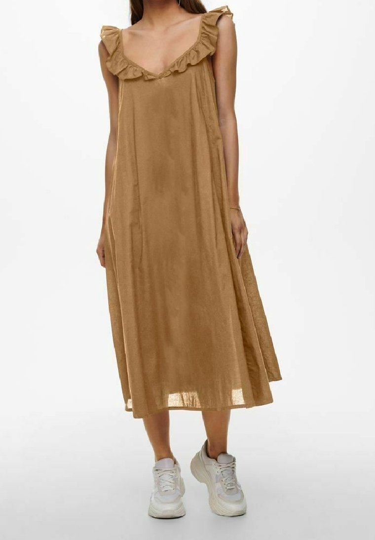 Robe midi marron sans manches avec un décolleté en V, des accents froncés sur les épaules et une coupe ample ; portée avec des baskets grises.