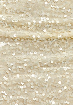 Tissu beige recouvert de sequins circulaires superposés, créant une surface texturée avec un léger éclat. Chaque sequin a un petit trou au centre.