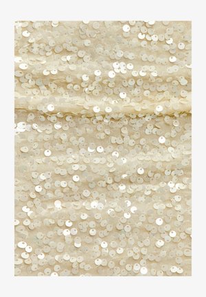 Tissu beige recouvert de sequins circulaires superposés, créant une surface texturée avec un léger éclat. Chaque sequin a un petit trou au centre.