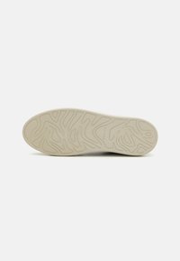 White rubber sneaker sole with textured patterns and grooves for traction. Smooth finish with the brand name subtly embossed.