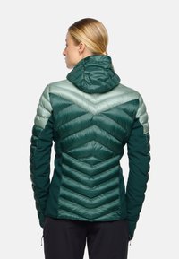 Giacca verde puffy con un design a zigzag, dotata di cappuccio, accenti in verde chiaro a contrasto e tessuto testurizzato sulle spalle e sulle maniche.