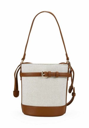 Bolso de lona beige tipo bucket con ribete de cuero marrón, correa de hombro ajustable y cinturón decorativo en la parte delantera.