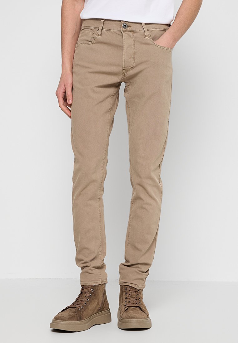 Beżowe spodnie z bawełny z dodatkiem stretchu o dopasowanym kroju, pięć kieszeni i zamek błyskawiczny. Charakteryzują się delikatnymi szwami i gładką fakturą.