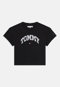 T-shirt en coton noir à manches courtes, portant le mot "TOMMY" dans un motif contrasté sur la poitrine et un petit logo sur la manche.