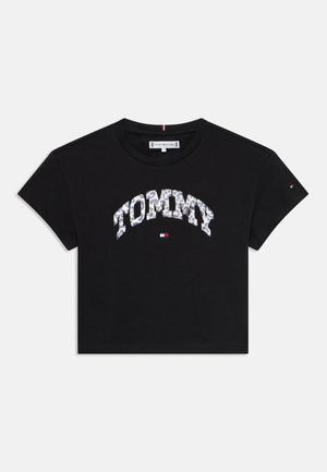 T-shirt en coton noir à manches courtes, portant le mot "TOMMY" dans un motif contrasté sur la poitrine et un petit logo sur la manche.
