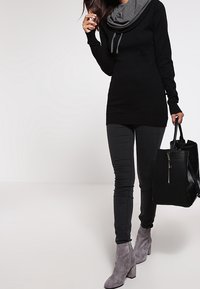 Černá tunika s šedým nazpět, spárovaná s tmavě šedými skinny džínami a šedými kotníkovými botami. Doplněná černou texturovanou kabelkou.