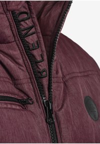 Dunkelrote gesteppte Jacke mit strukturierter Oberfläche, schwarzem Reißverschluss und gesticktem "CLEANED"-Detail vorne. Verfügt über ein Logo-Patch.