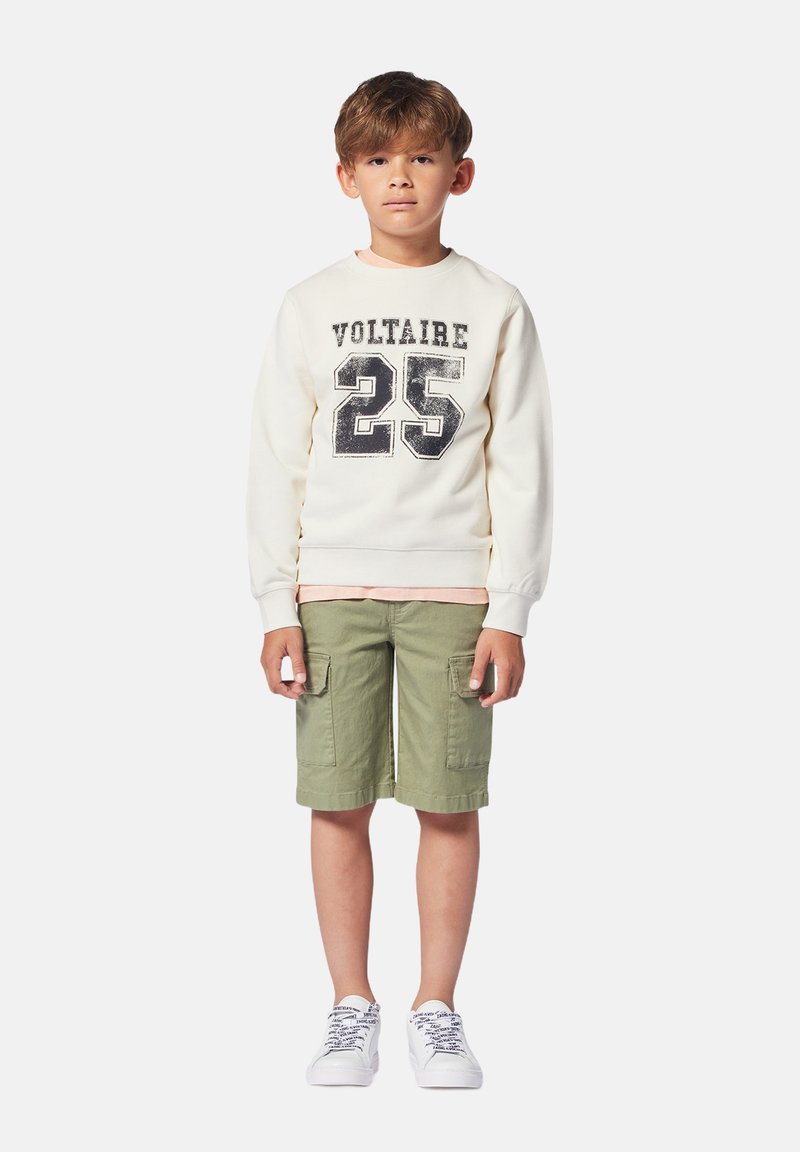 Felpa bianca con stampa "VOLTAIRE 25", pantaloni cargo verde oliva e sneakers bianche. Tessuto in cotone e design casual.