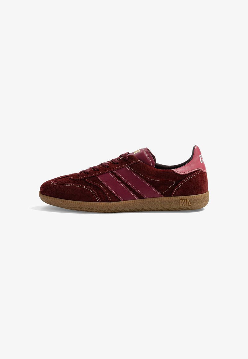Baskets basses bordeaux avec dessus en daim et cuir, semelle en gomme, bandes cousues sur le côté et languette de talon brandée.