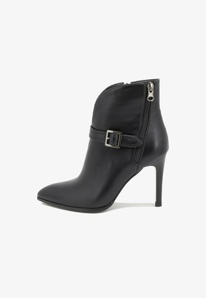 Bota de cuero negro para tobillo con punta afilada, cierre de cremallera y detalle de hebilla. Cuenta con un tacón alto de aguja y textura suave.