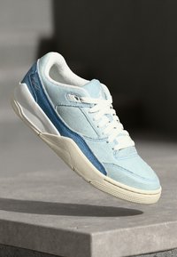 Baskets bleu clair avec un matériau en denim, une semelle en caoutchouc blanche et des accents bleu foncé contrastants. Design classique à lacets avec détails de couture.
