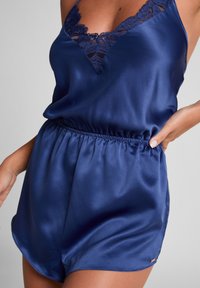 Navy Satin-Romper mit Spitze, V-Ausschnitt und elastischem Taillenbund. Glatte Textur und leicht ausgestellte Shorts.